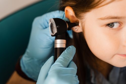 Close-up examination of childs ear with otoscope. Otoscopy. Visit to ENT doctor and consultation